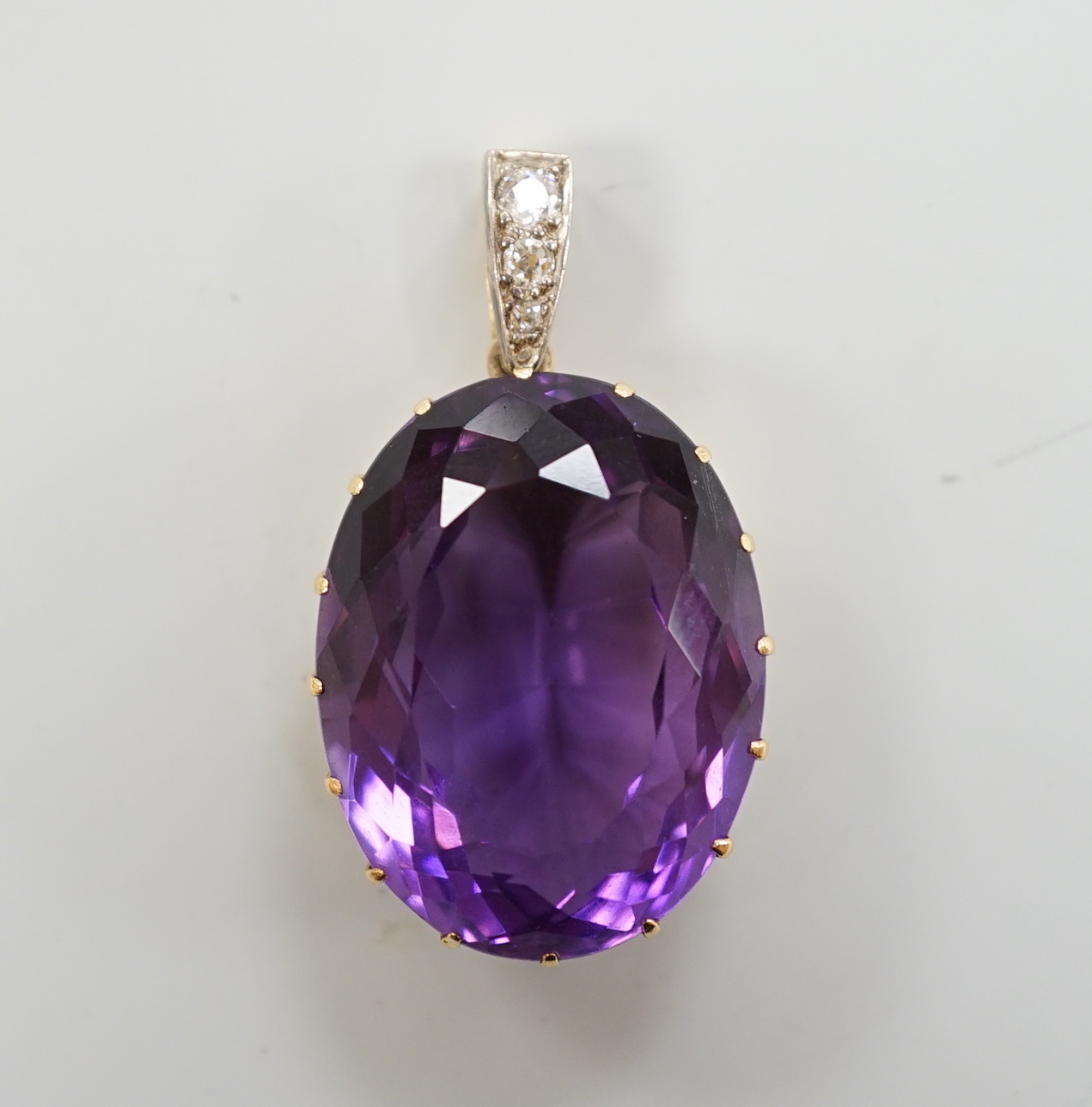 An Edwardian yellow metal, oval cut amethyst and three stone diamond set drop pendant, overall 4cm, gross weight 16.7 grams.